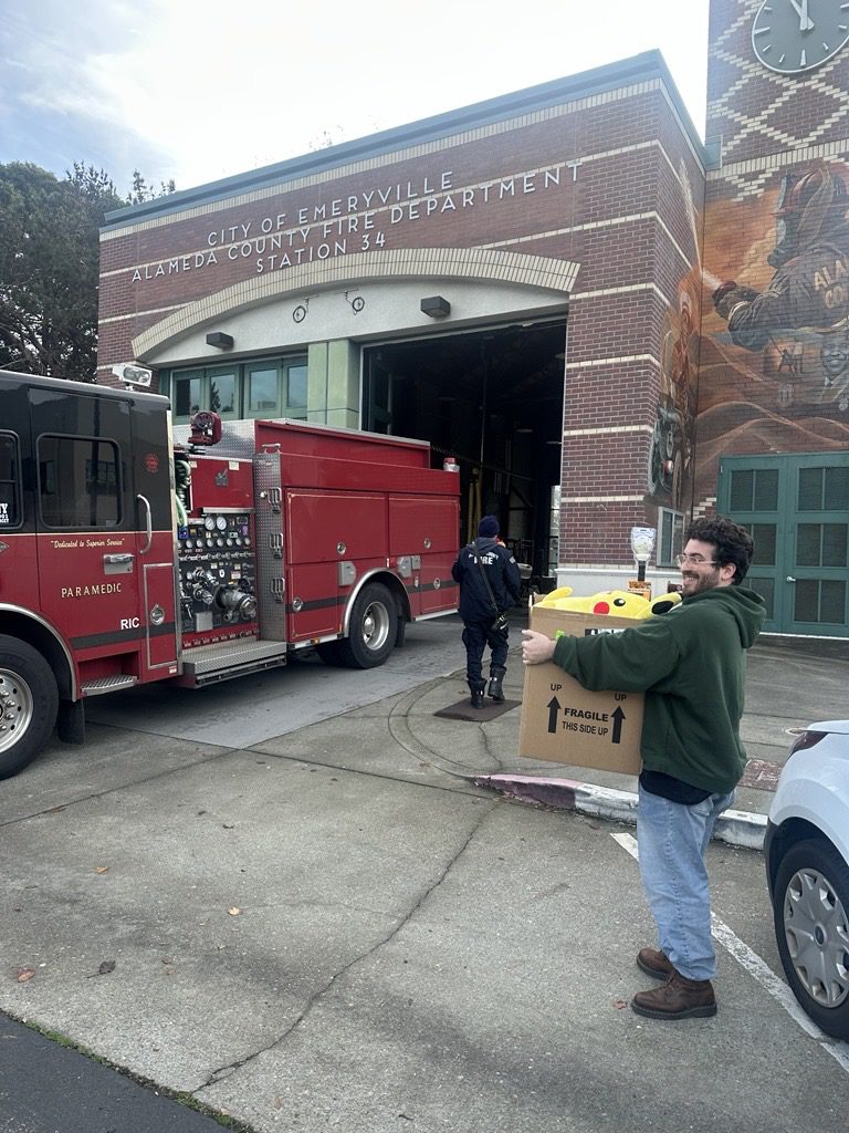 The toys being carried into a fire station by a PC Professional team member and a fireman.