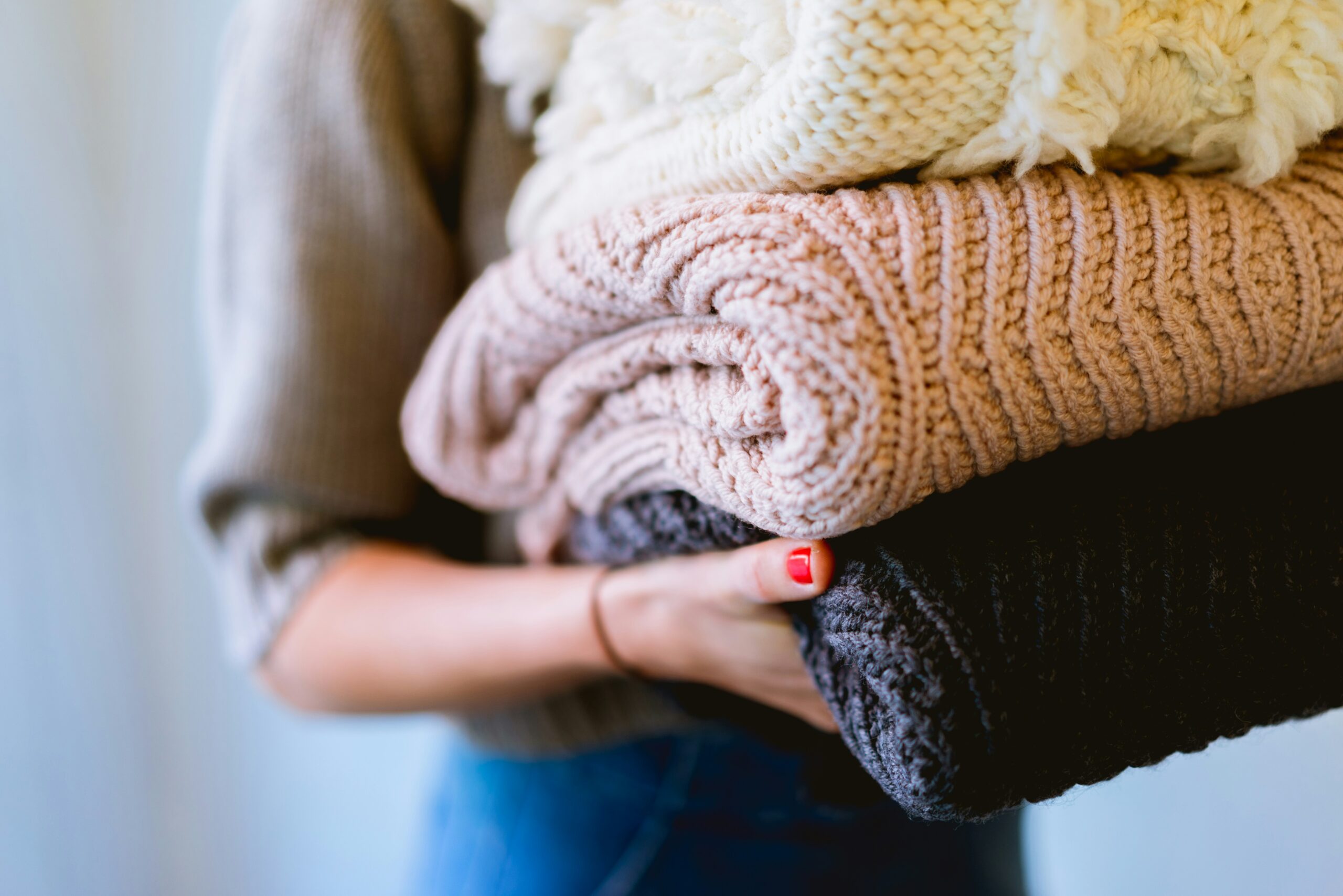 A woman carrying folded knit textiles.